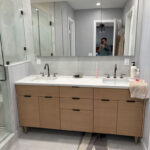 Modern bathroom remodel featuring sleek double vanity with quartz countertop, black fixtures, and elegant lighting.