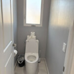 Refreshed bathroom with light grey walls, open shelving, and stylish wood accents.