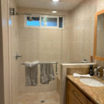 Pre-renovation bathroom with worn flooring, older cabinetry, and minimal lighting.