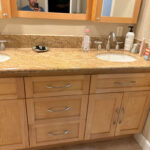 Outdated bathroom with beige tiled walls, an old-fashioned vanity, and basic fixtures in need of renovation.