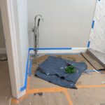 Renovated shower with modern tile design and handheld shower head under large skylight during final construction.
